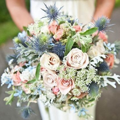 Low table centrepiece of seasonal blooms and trailing foliage on a reception table