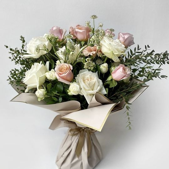 Flower arrangement of seasonal blooms and greenery in soft daylight